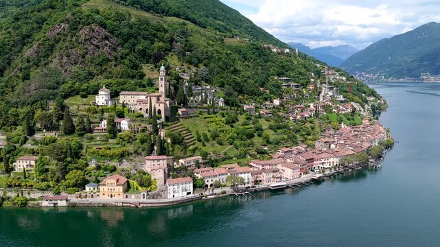Aerial view of the historic village of Morcote with its traditional stone buildings and church tower nestled on the shores of Lake Lugano in Lugano, Ticino, Switzerland.