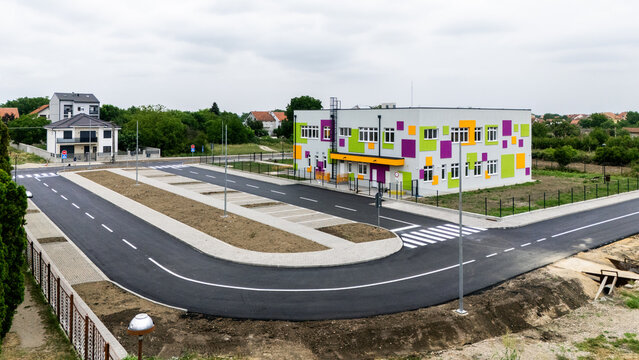Aerial view of a modern building with colorful geometric facade patterns, surrounded by a newly paved road and parking area in Pancevo, Vojvodina, Serbia.