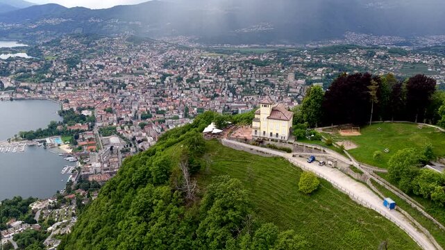 Aerial view of Monte Bre overlooking the city of Lugano with lush green slopes and urban architecture in Lugano, Ticino, Switzerland.