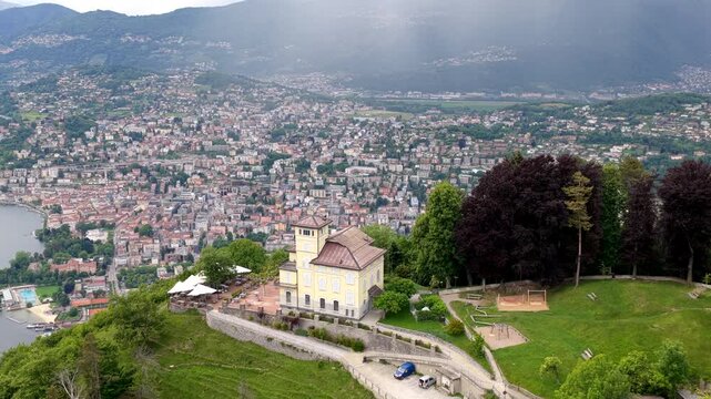 Aerial view of the historic villa on Monte Bre overlooking the city of Lugano and Lake Lugano with lush green slopes and trees in Lugano, Ticino, Switzerland.