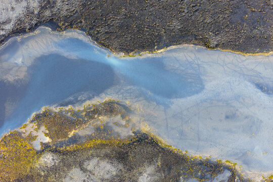 Aerial view of a glacial river winding through volcanic black sand and mossy terrain near Vik, Myrdalshreppur, Iceland.