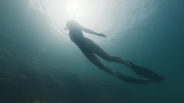 Young slim woman swims underwater, freediving and snorkeling in the sea near the coral reef near the island of Ilha Grande in Brazil