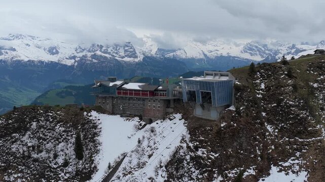 Aerial view of the Stanserhorn Cabrio cable car station perched on the mountain ridge with snow-dusted slopes and alpine peaks in the background in Stans, Nidwalden, Switzerland.
