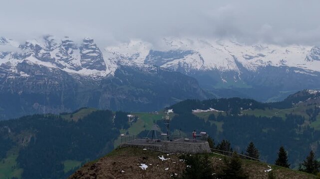 Aerial view of the Stanserhorn Cabrio observation deck surrounded by snow-capped mountains and green alpine slopes in Stans, Nidwalden, Switzerland.
