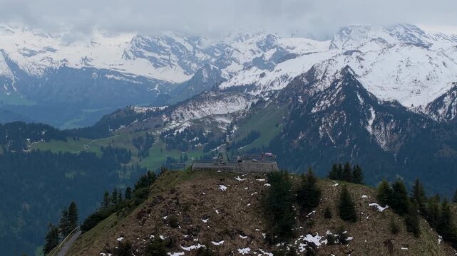 Aerial view of the Stanserhorn Cabrio viewing platform surrounded by snow-capped peaks and lush green mountain slopes in Stans, Nidwalden, Switzerland.