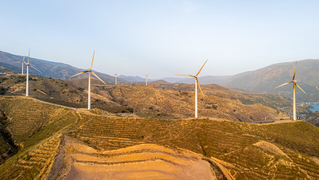 Aerial view of wind turbines standing on rolling hills in the dry landscape of Velez de Benaudalla, Andalusia, Spain.