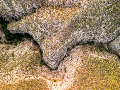 Aerial view of a rugged rocky gorge with steep cliffs and dry vegetation in Velez de Benaudalla, Andalusia, Spain.