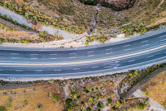 Aerial view of a highway curving through the dry, hilly landscape of Velez de Benaudalla, Andalusia, Spain.