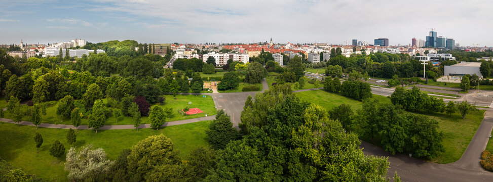 Poznan, Poland - 19 June 2026: Aerial view of the lush green park in the foreground with walking paths and trees, leading to the urban skyline of Poznan.