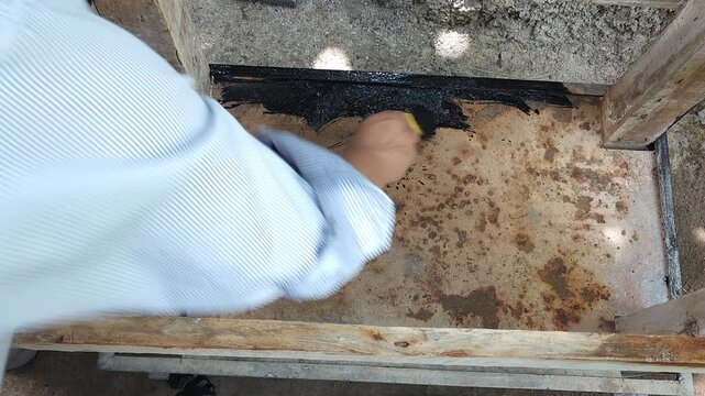 Applying First Brush Strokes of Black Paint to Rusty Metal Sheet