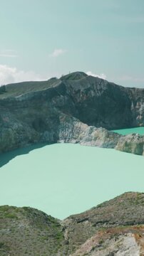 A person stands atop a mountain, gazing at a lake in the Philippines. The scene captures a volcanic crater lake in the distance.