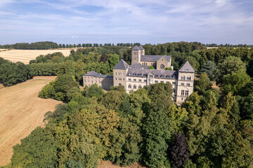 Obraz premium Aerial of abbey and monastery Gerleve Kloster in German hill landscape. Religious monk community building in agriculture scenery seen from above with a blue sky. 