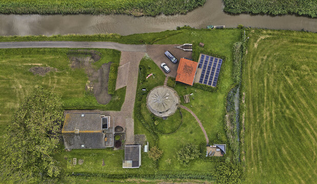 Lage Zwaluwe, North Brabant, Netherlands - 04 June 2026: Aerial view of the stone tower of the former Polder Schuddebeurs drainage mill, now a residence, with a canal and solar panels.