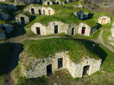 Aerial view of the historic stone palmenti, traditional rock-cut wine cellars built into the grassy hillside in Pietragalla, Basilicata, Italy.