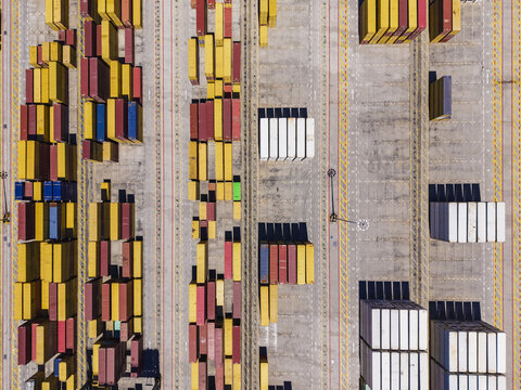 Aerial view of the Port of Sines, featuring rows of colorful shipping containers arranged in a grid pattern on the concrete terminal yard Sines, Setubal, Portugal.