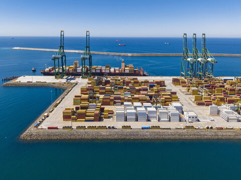 Aerial view of the Port of Sines with large container ships, gantry cranes, and stacks of colorful shipping containers on the terminal dock in Sines, Setubal, Portugal.
