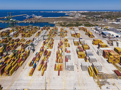 Aerial view of the busy container terminal in the port of Sines with rows of colorful shipping containers, large cranes, and industrial infrastructure in Sines, Setubal, Portugal.