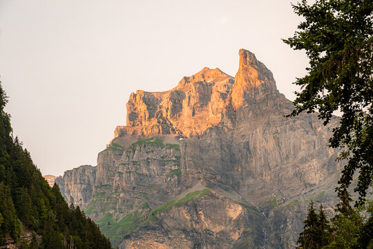 View of the Cirque du Fer a Cheval illuminated by golden hour light with rocky cliffs and green slopes in Sixt-Fer-a-Cheval, Auvergne-Rhone-Alpes, France.