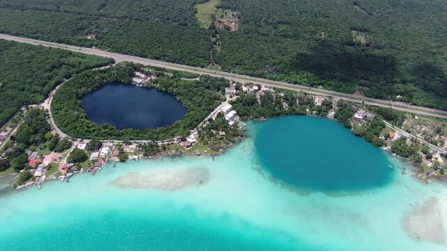Aerial view of the vibrant turquoise waters of Laguna de Bacalar and its deep blue cenotes surrounded by lush tropical forest in Bacalar, Quintana Roo, Mexico.