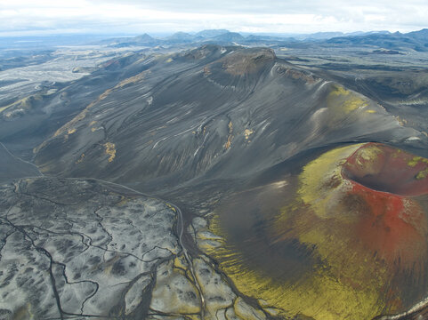 Aerial view of Raudaskal crater with its vibrant red volcanic slopes and surrounding mossy lava fields in Rangarthing ytra, Iceland.
