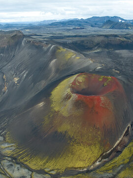 Aerial view of the vibrant red and green Raudaskal crater surrounded by dark volcanic slopes and rugged Icelandic terrain in Akureyri, Rangarthing ytra, Iceland.
