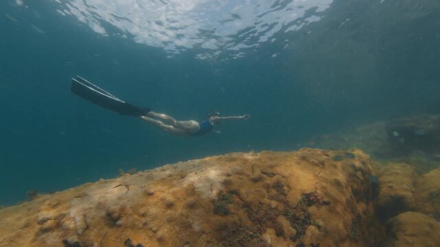 Young slim woman swims underwater, freediving and snorkeling in the sea near the coral reef near the island of Ilha Grande in Brazil