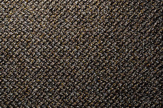 Texture of grey brown loop pile carpet flooring macro. Detailed closeup of commercial loop pile carpet texture in brown and grey tones with diagonal studio light