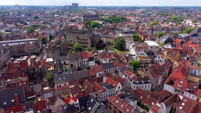 Aerial view video clip of historical Gravensteen castle, traditional Flemish gabled houses, red tile roofs, and expansive urban cityscape of Ghent in Belgium on a daylight summer day