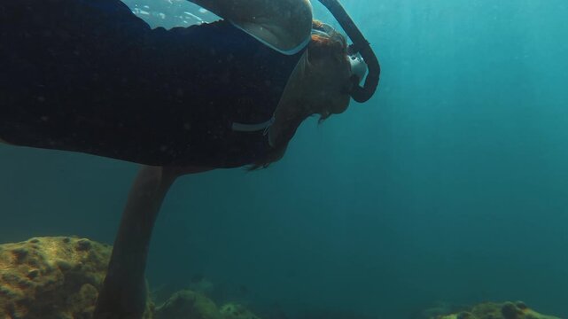 Young slim woman swims underwater, freediving and snorkeling in the sea near the coral reef near the island of Ilha Grande in Brazil