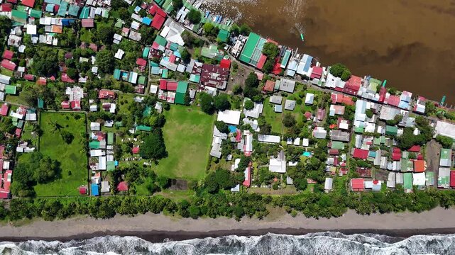Aerial view of colorful village rooftops nestled between the lush green landscape and the Caribbean Sea in Tortuguero, Limon Province, Costa Rica.