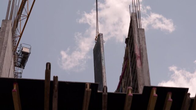 Tower crane installing wall formwork panels at construction site low angle
