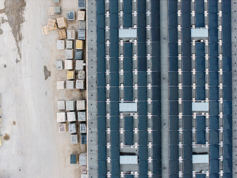 Aerial view of a manufacturing facility featuring rows of solar panels on the roof and stacks of concrete paving stones on the ground in Riga, Latvia.