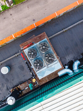 Aerial view of industrial HVAC units with four large fans and metal piping on a flat rooftop in Riga, Latvia.