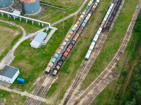 Aerial view of freight train tank cars parked on parallel tracks at an industrial facility in Latvia.