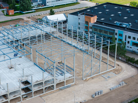 Aerial view of a steel frame construction site for an industrial building with concrete foundations and metal beams in Riga, Latvia.