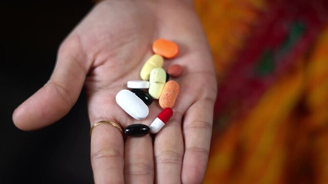 Close up shot of open hand holding various colorful medical pills capsules and tablets. diverse prescription medicine pills and drug capsules in human palm.