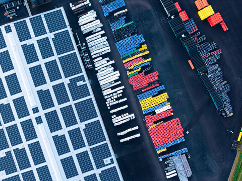 Aerial view of the Evopipes manufacturing facility with rows of colorful plastic pipes stored in the yard and solar panels on the roof in Jelgava, Latvia.
