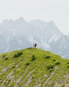 Aerial view of hikers standing on the grassy ridge of Col de la Puina with the majestic Dolomite mountains in the background in Borca di Cadore, Veneto, Italy.