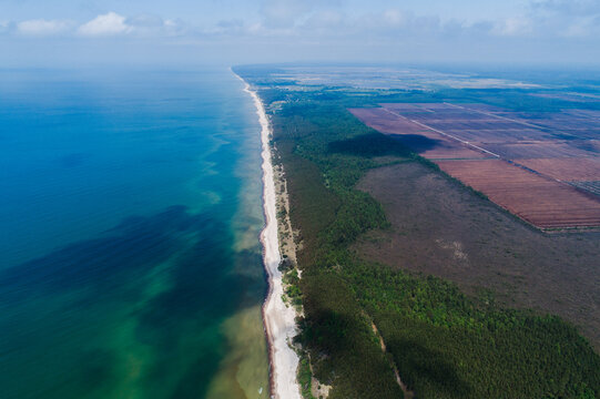 Aerial view of Nida Bog and the Baltic Sea coastline, featuring peatland habitats, dense forest, and sandy beach in Nida, South Kurzeme Municip, Latvia.
