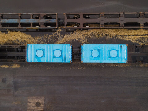 Aerial view of a freight train with blue tank containers on a dark industrial surface in Riga, Latvia.