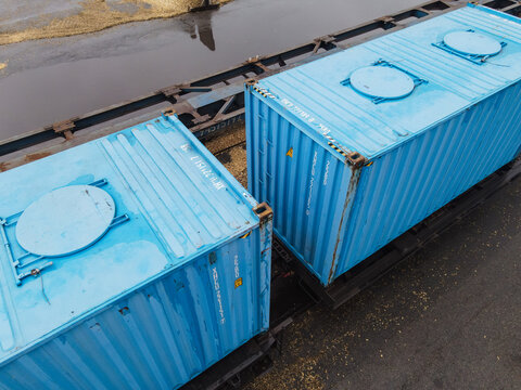 Aerial view of two bright blue shipping containers loaded on a flatbed train car in Riga, Latvia.