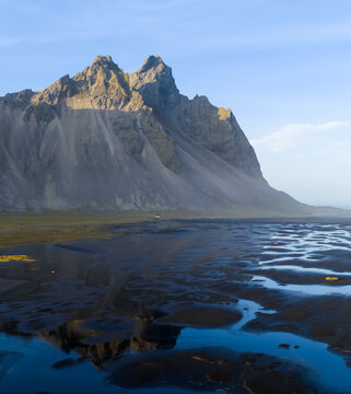 Aerial view of Vestrahorn Mountain reflecting in the tidal flats of the black sand beach in Hofn, Sveitarfelagid Hornaf, Iceland.