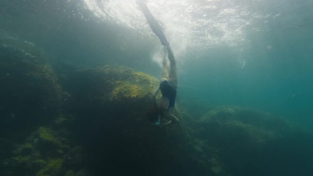 Young slim woman swims underwater, freediving and snorkeling in the sea near the coral reef near the island of Ilha Grande in Brazil