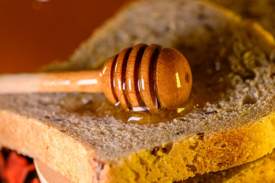 Golden honey and fresh bread slices beside glass jar in warm rustic kitchen setting