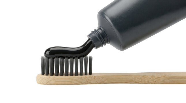 Black charcoal toothpaste being squeezed onto a bamboo toothbrush isolated on transparent background