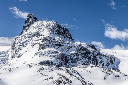 View of the snow-covered Matterhorn peak under a clear blue sky with ski lift cables visible in Zermatt, Valais, Switzerland.