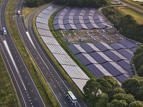 Den Oever, Netherlands - 19 June 2026: Aerial view of a solar farm under construction on the Highway A7 embankment, part of the Afsluitdijk renovation project, with traffic on the road.