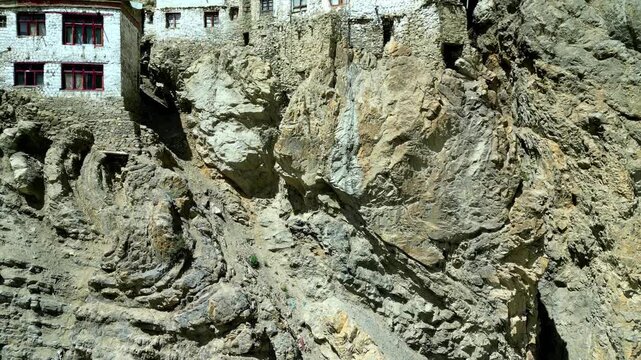 Aerial view of the ancient Phukthal Gompa monastery built into a steep rocky cliffside in the Zanskar region, Phugtal, Himachal Pradesh, India.