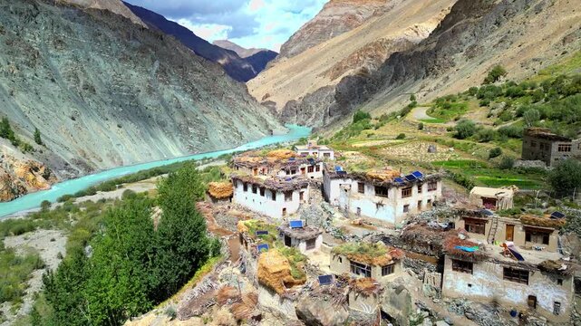 Aerial view of the historic Phukthal Gompa monastery nestled in the rugged mountains of Zanskar, with the turquoise Lungnak River flowing through the valley in Phugtal, Himachal Pradesh, India.