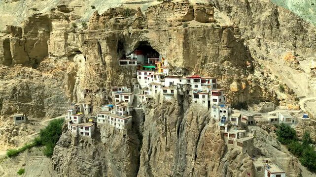 Aerial view of Phukthal Gompa, a historic monastery built into a cliffside with white buildings and rocky terrain in Phugtal, Himachal Pradesh, India.